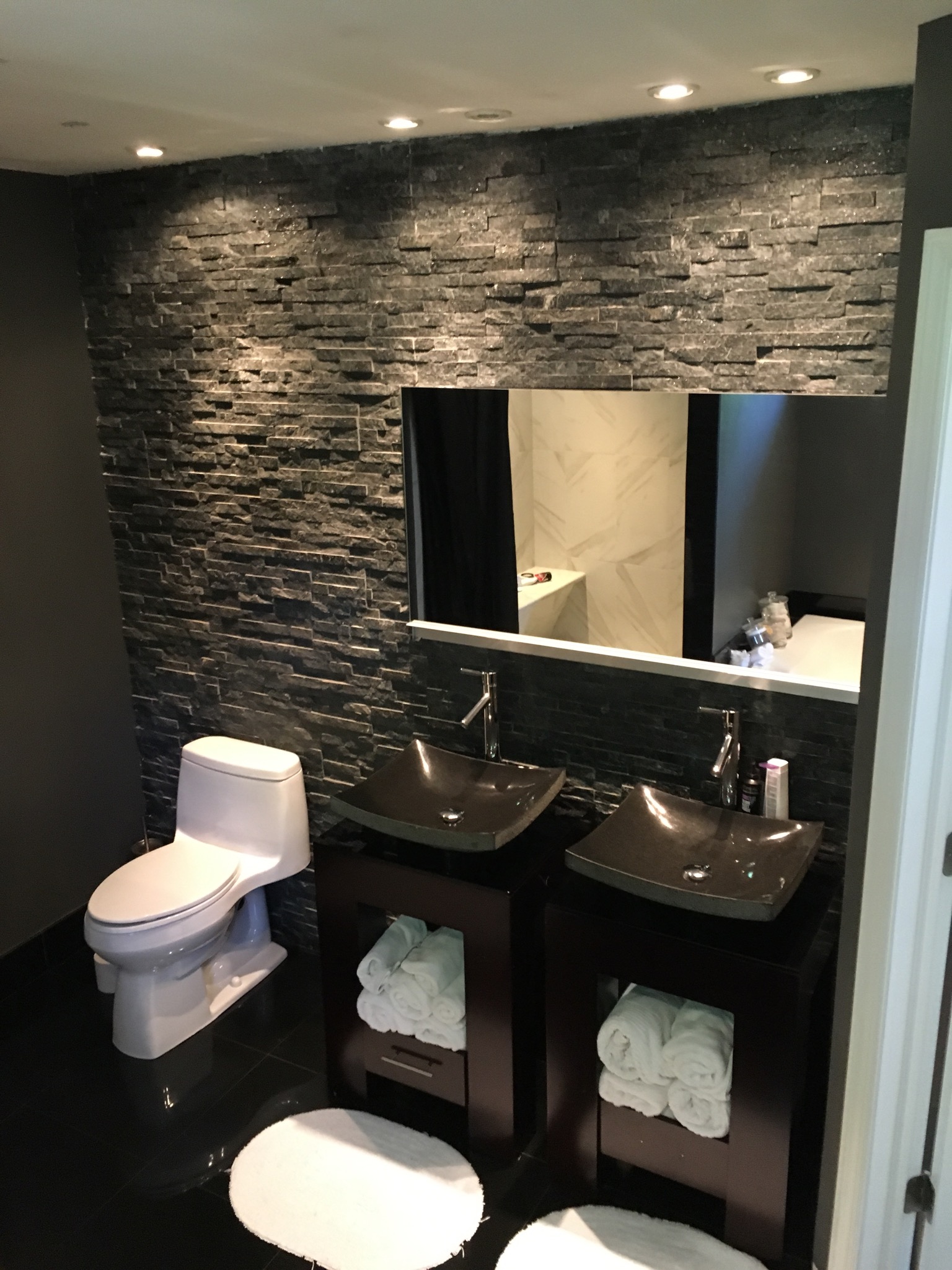 Bathroom with stacked stone feature wall and twin granite vessel sinks, Westchester County